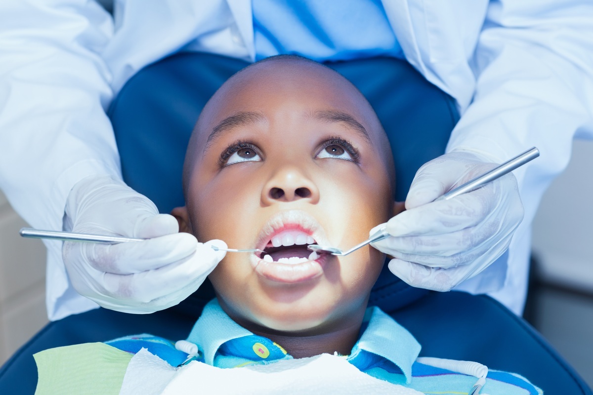 Criança no consultório do dentista tendo seus dentes examinados - foto: wavebreakmedia/ShutterStock.com