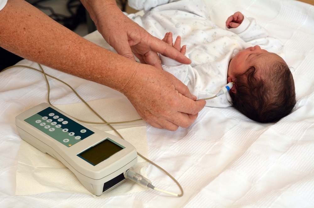Bebê recém-nascido durante triagem auditiva neonatal (teste da orelhinha) - foto: ChameleonsEye/ShutterStock.com