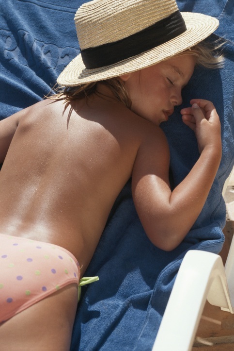 Criança deitada tomando banho de sol em horário inadequado - GettyImages