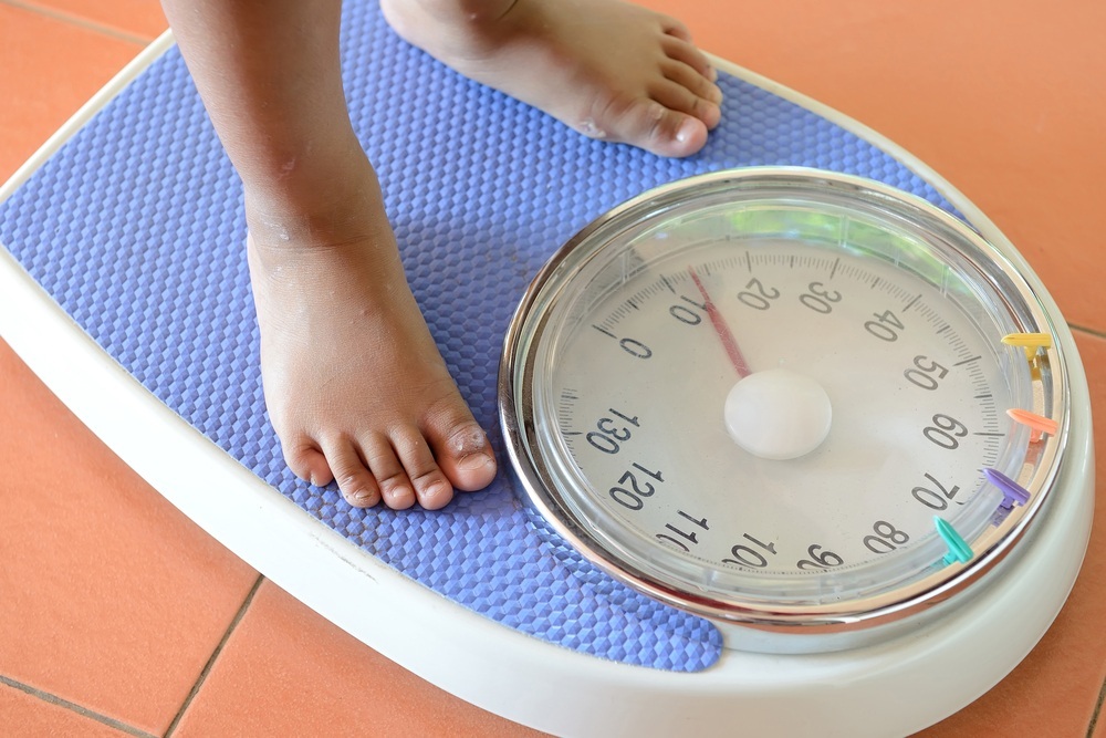 Criança sobre uma balança verificando o peso - foto: Sarit Wuttisan/ShutterStock.com
